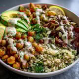 Roasted red bell peppers and zucchini top a vibrant Vegetable and Legume Bowl with creamy avocado slices.