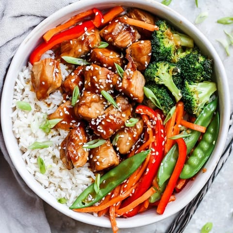 A close-up of a homemade Teriyaki Chicken Bowl garnished with sesame seeds and green onions, ready to serve for dinner.