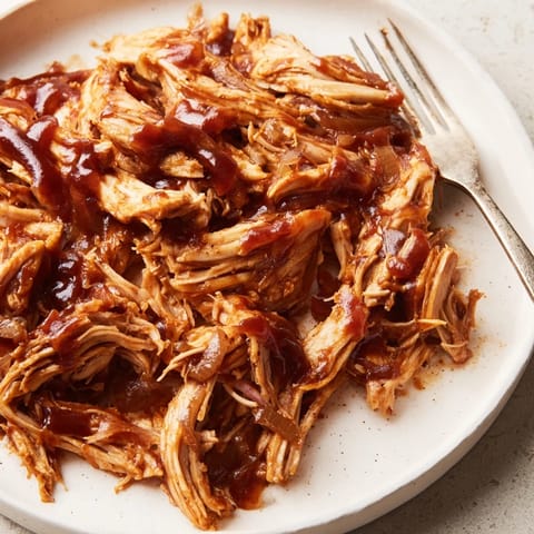 Tender, slow-cooked BBQ Pulled Chicken piled high on a soft sandwich bun with creamy coleslaw.