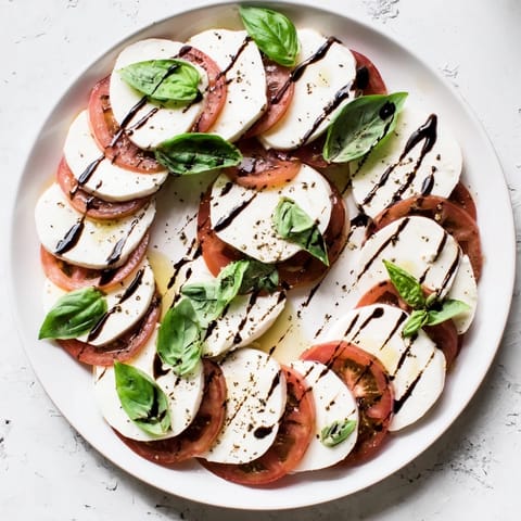 Fresh Caprese Salad is garnished with sea salt and black pepper, ready to serve as a side dish.