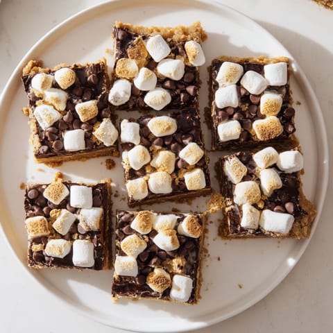 Golden-toasted marshmallows melt over rich chocolate on a buttery graham cracker base in these homemade S'mores Bars.