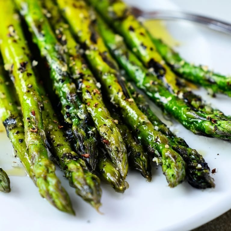 Vibrant green Grilled Asparagus spears glistening with olive oil and lemon juice on a rustic wooden serving platter.