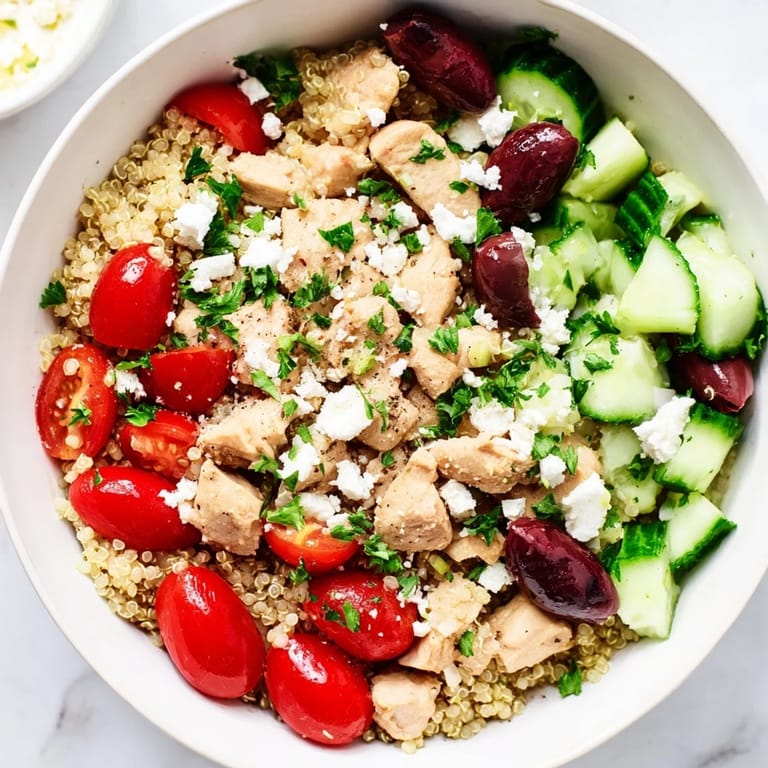 Scattered ingredients around a finished Mediterranean Chicken Bowl, showcasing bright colors and zesty lemon dressing.