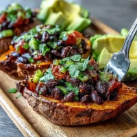 Garnished with avocado slices and cilantro, this wholesome roasted sweet potatoes with chipotle black beans and zesty tomato salsa meal is served warm.
