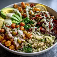 Roasted red bell peppers and zucchini top a vibrant Vegetable and Legume Bowl with creamy avocado slices.